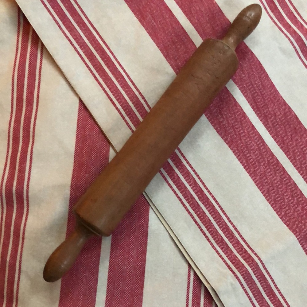 Vintage one-piece solid dark brown rolling pin.